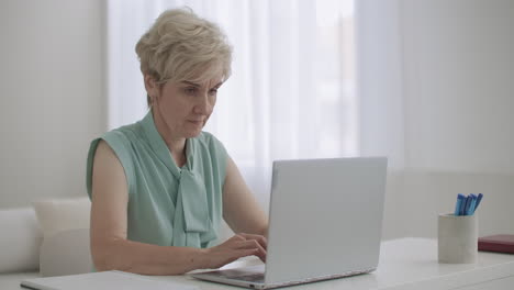 Una-Anciana-Trabaja-Remotamente-Usando-Una-Computadora-Portátil-Con-Conexión-A-Internet-Para-Comunicar-Mensajes-Escritos-En-Un-Chat-En-Línea
